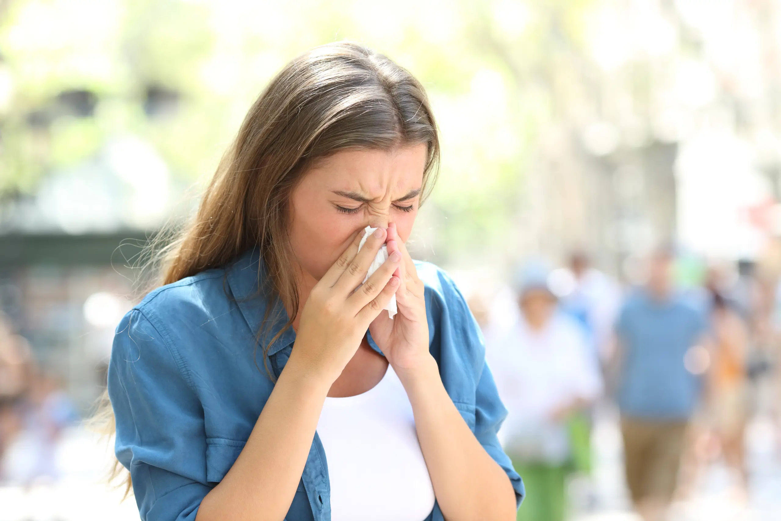 Kvinne som holder et lommetørkle foran nesen og nyser