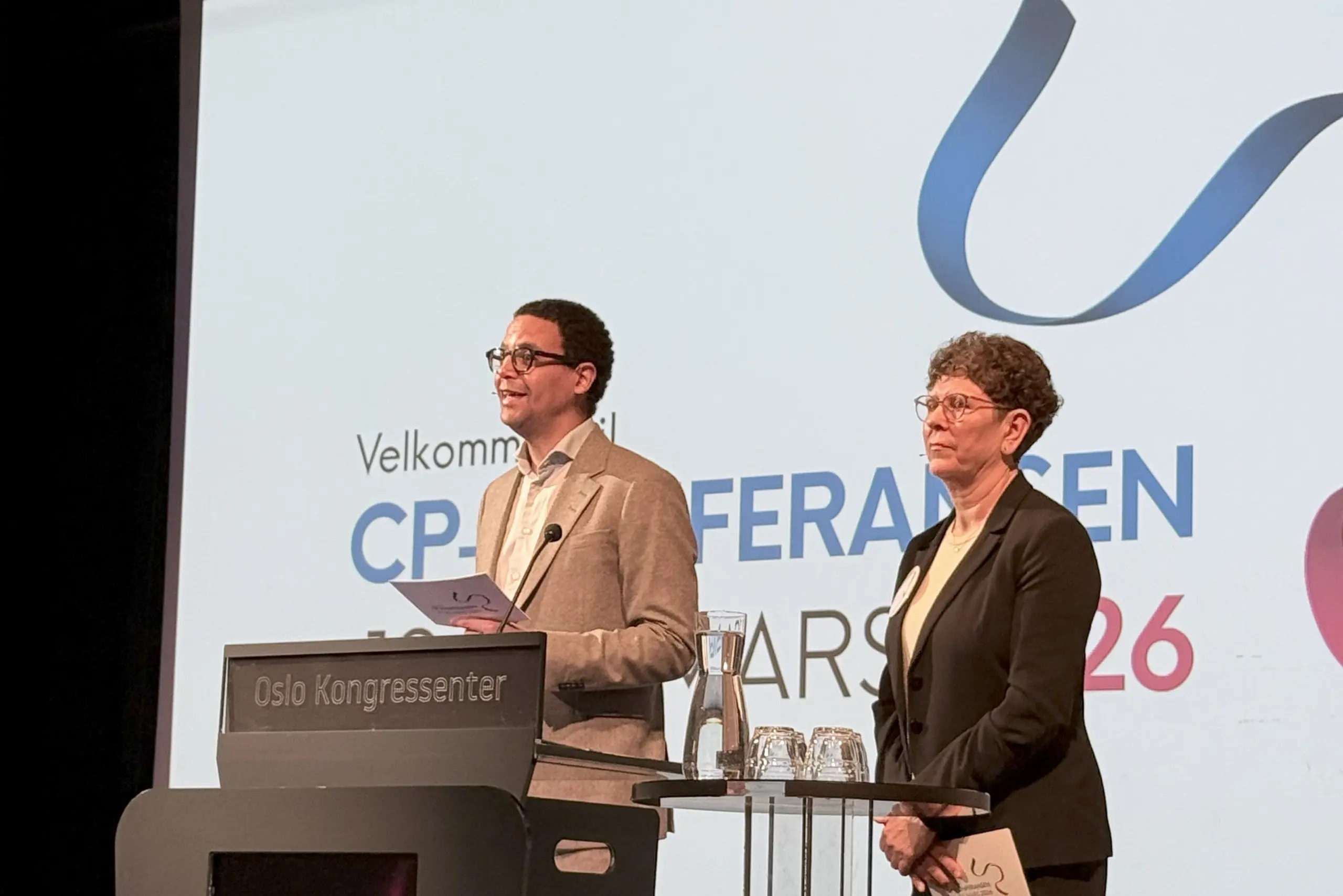 En mann som holder en tale og en kvinne som står ved siden av