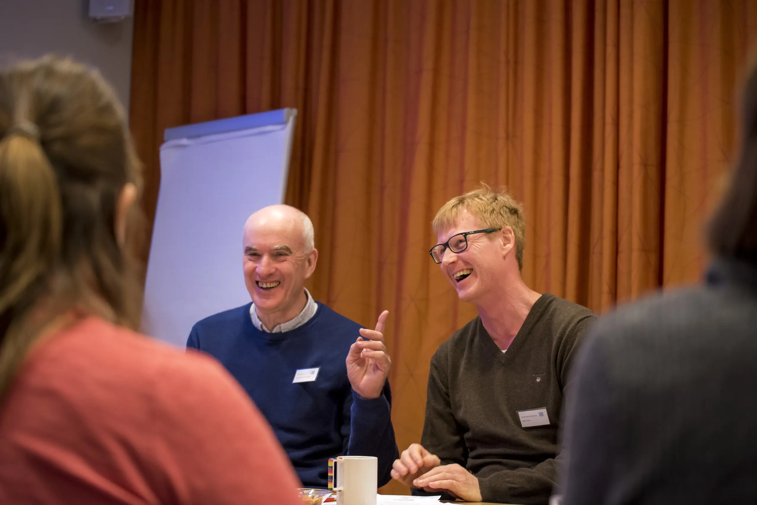 To smilende menn i et rom