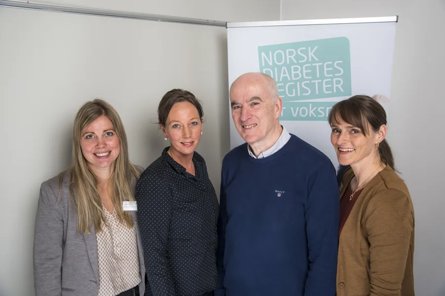 Tre kvinner og en mann som smiler og ser i kamera