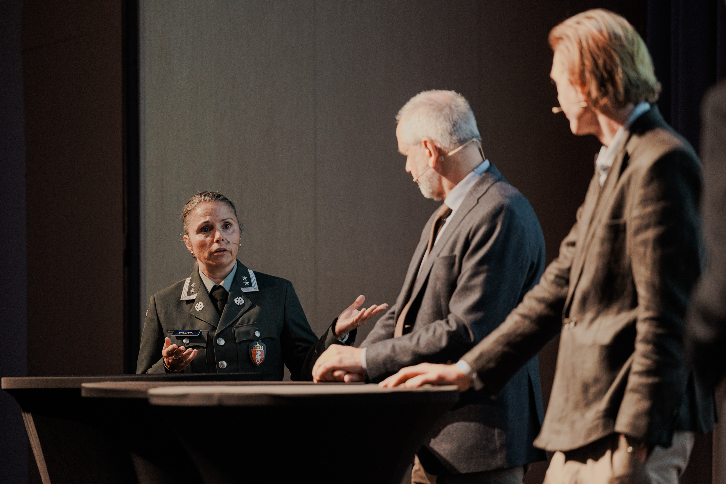 To menn og en kvinne som står rundt et bord