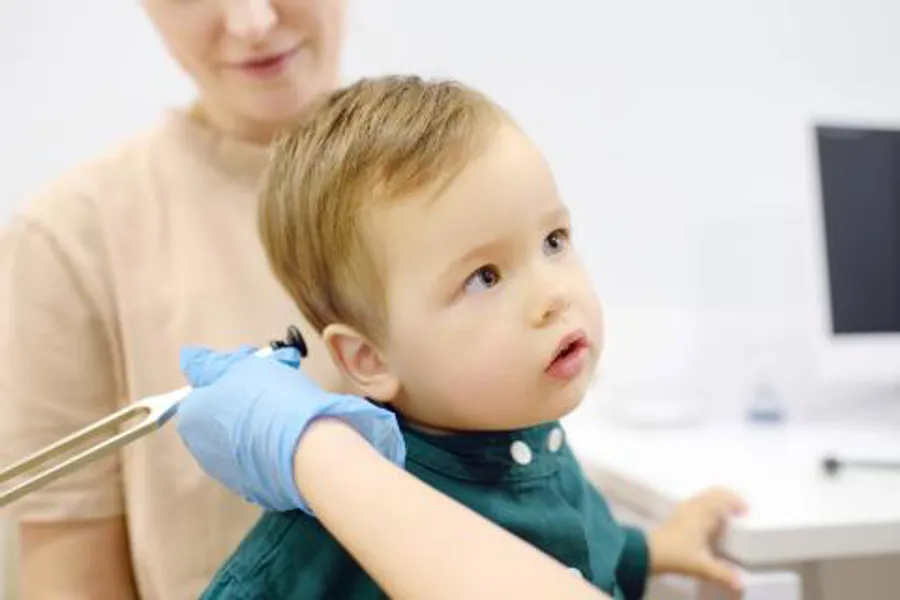 En baby som holdes av en person og gjør en hørselsundersøkelse