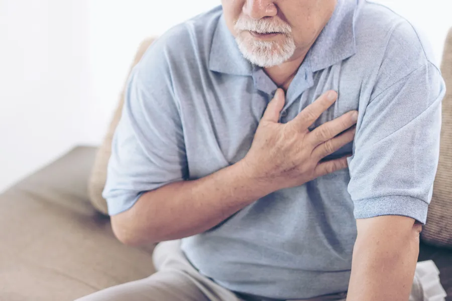 Mann som holder seg til brystet